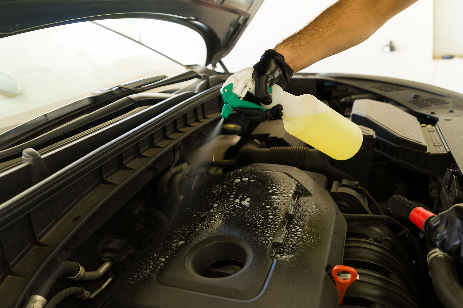 Washing car engine with spray in detailing auto service